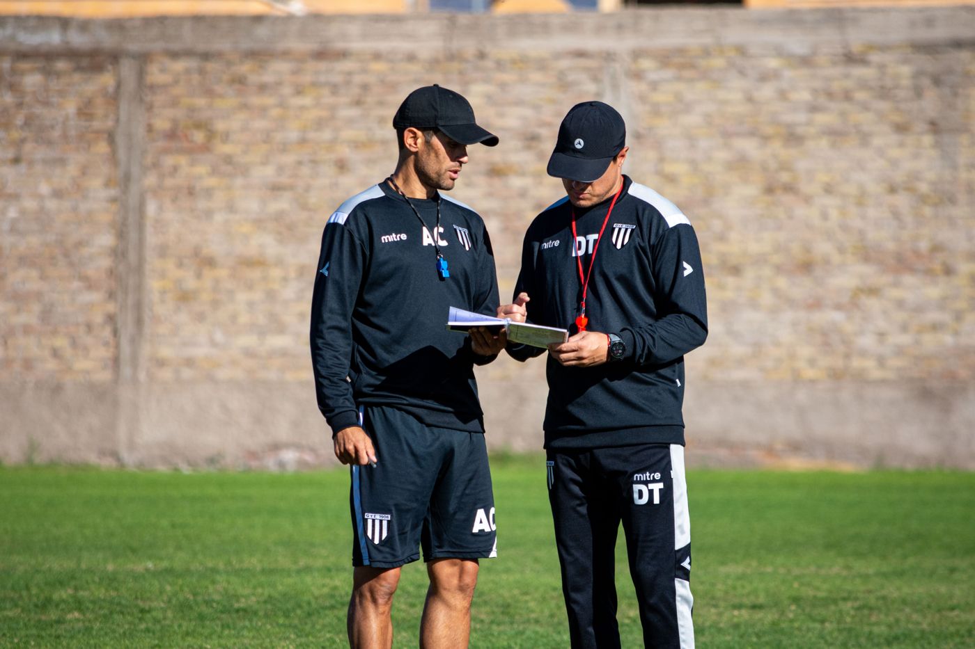 Dos entrenadores revisando anotaciones en la cancha