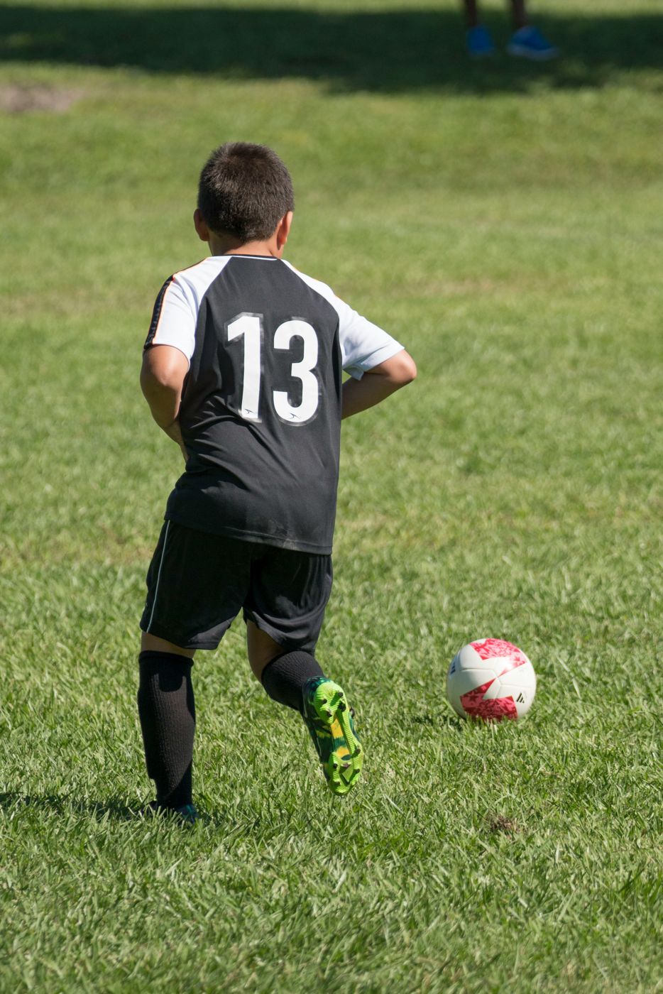 Niño con playera número 13 conduciendo el balón